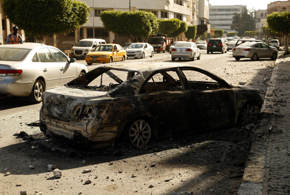 A car burned during clashes remains on a street in the Libyan capital of Tripoli, Sunday, Aug. 28 2022. Deadly clashes broke out Saturday in Libya's capital between militias backed by its two rival administrations, portending a return to violence amid a long political stalemate. (AP Photo/Yousef Murad)