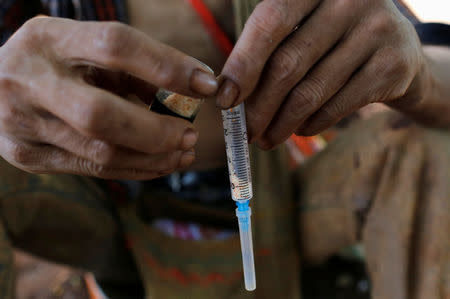 A man prepares to inject heroin along a street in Man Sam, northern Shan state Myanmar July 11, 2016. REUTERS/Soe Zeya Tun