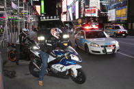 In this Saturday, May 2, 2020 photo, a police car slows down as an officer barks orders through a microphone to parked motorcyclists to keep on moving in New York's Times Square during the coronavirus pandemic. (AP Photo/Mark Lennihan)