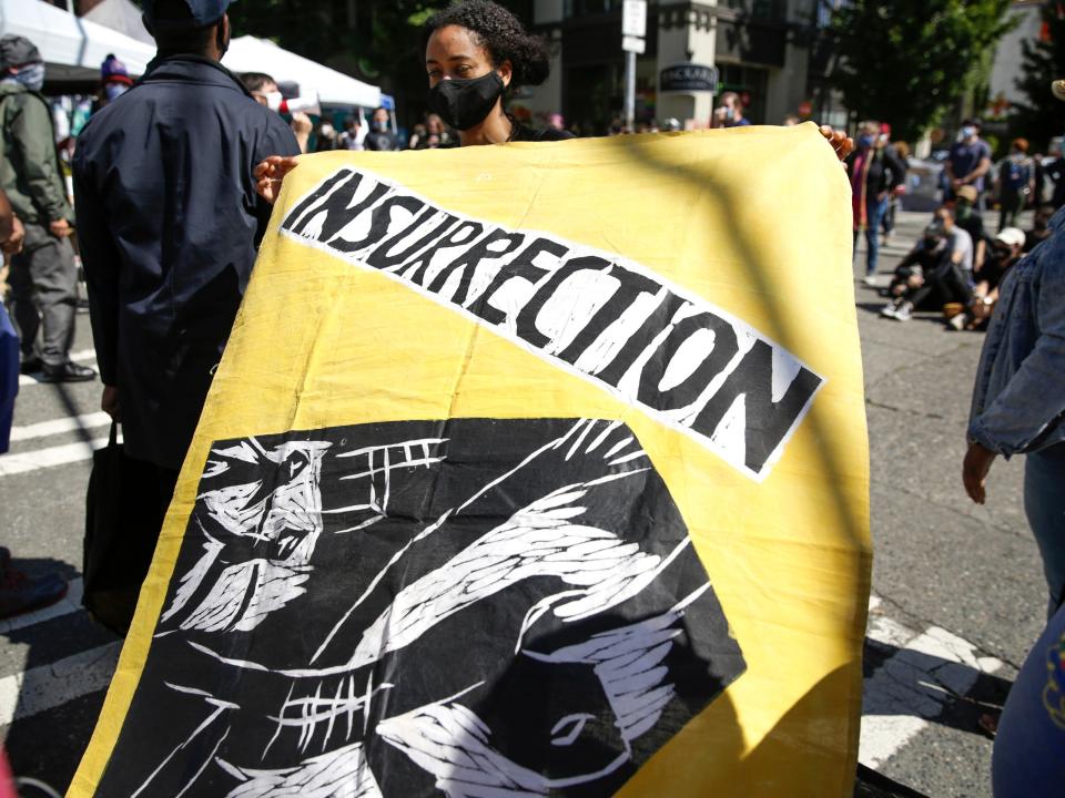A protester holds an "insurrection" flag that Human Rights Attorney Mike Withey saved from the WTO Seattle protests as people gather in the newly created Capitol Hill Autonomous Zone (CHAZ), in Seattle, Washington on June 11, 2020. Jason Redmond/AFP via Getty Images