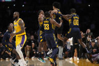 Indiana Pacers guard Andrew Nembhard, second from right, celebrates with teammates after making a buzzer beating 3-point shot to win the game as Los Angeles Lakers forward LeBron James walks off the court during the second half of an NBA basketball game Monday, Nov. 28, 2022, in Los Angeles. The Pacers won 116-115. (AP Photo/Mark J. Terrill)