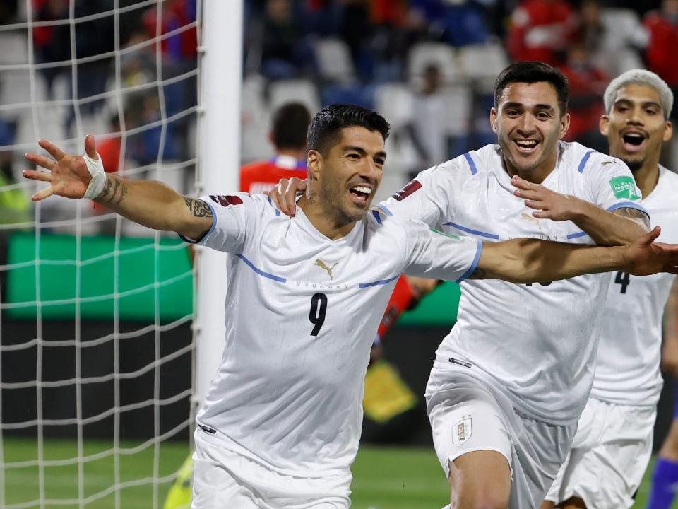 Luis Suarez runs with his arms out after a goal as teammates follow him during a Uruguay soccer match.