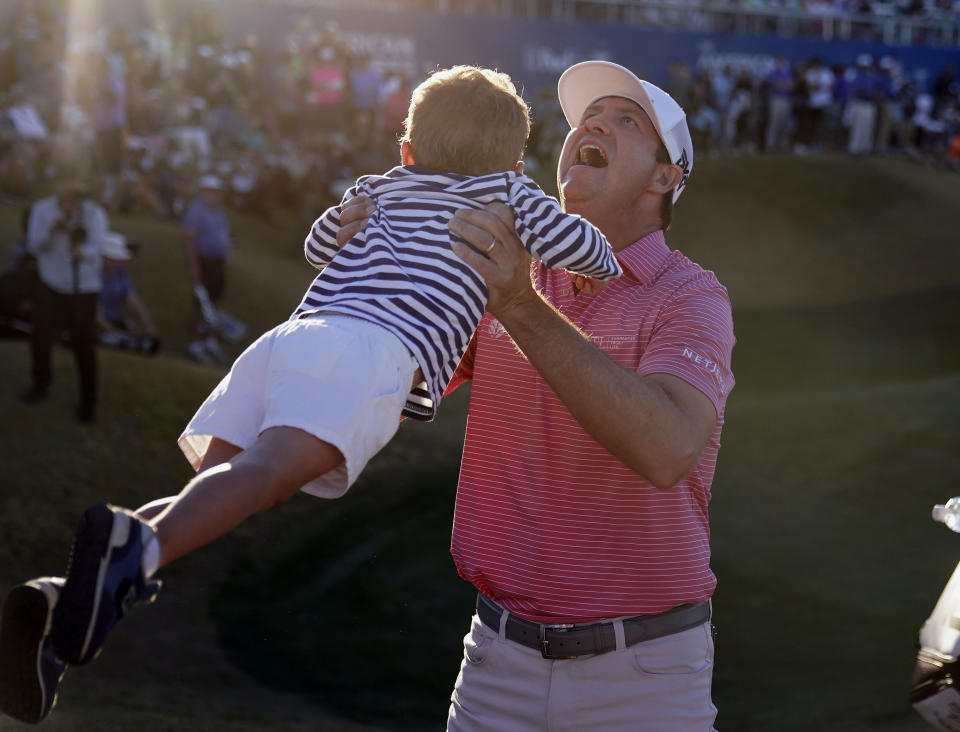 Hudson Swafford lifts his son James after winning the American Express golf tournament on the Pete Dye Stadium Course at PGA West, Sunday, Jan. 23, 2022, in La Quinta, Calif. (AP Photo/Marcio Jose Sanchez)