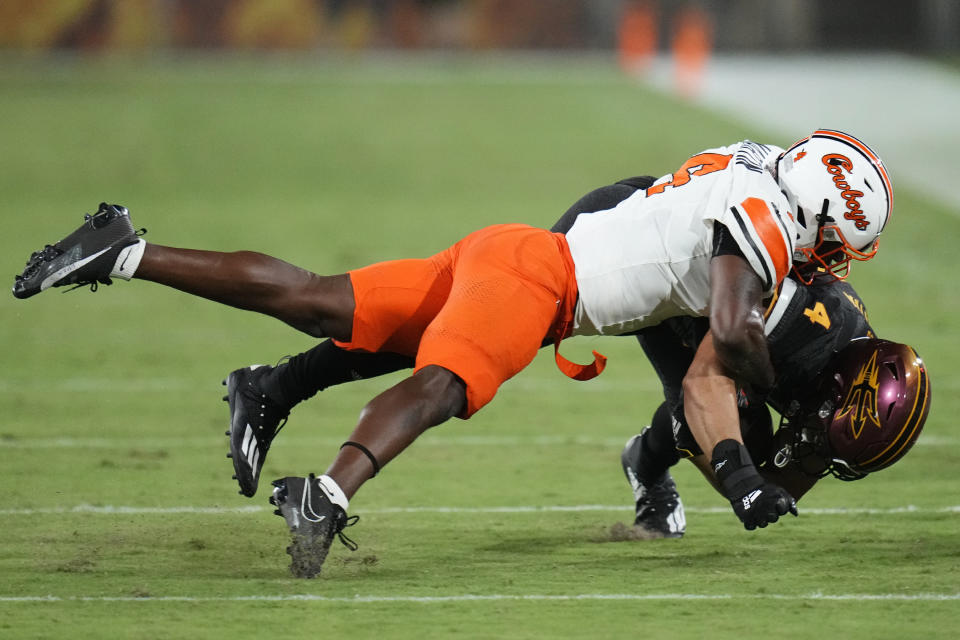 Oklahoma State linebacker Nickolas Martin, left, tackles Arizona State running back Cameron Skattebo (4) during the first half of an NCAA college football game Saturday, Sept. 9, 2023, in Tempe, Ariz. (AP Photo/Ross D. Franklin)