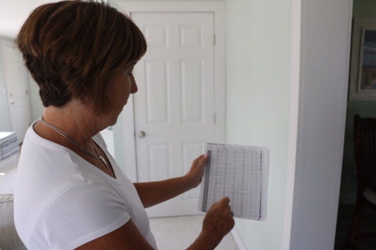 Debra Bourbeau looks at a tidal chart that she uses to predict when the streets will flood. Bourbeau moves her car to higher ground whenever there’s a 10-foot tide.