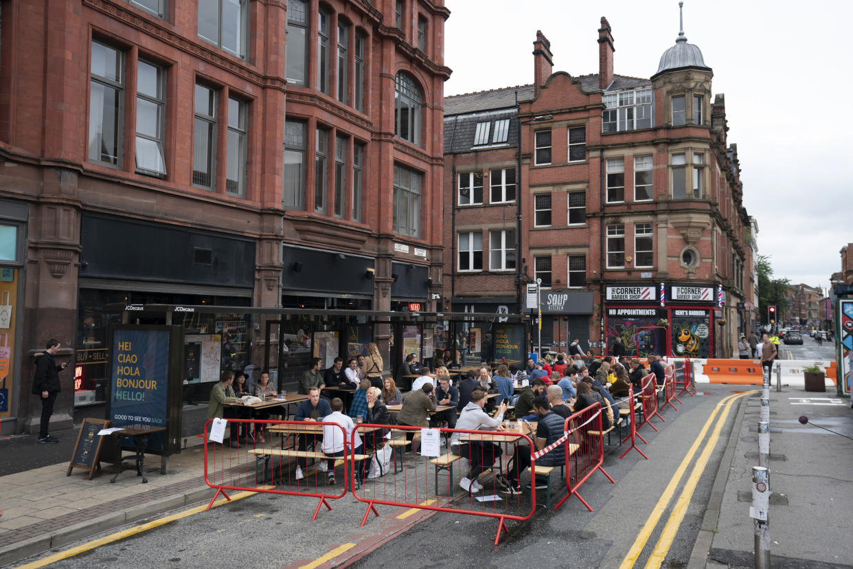 Members of the public are seen at a bar in Manchester's Northern Quarter, England, Saturday July 4, 2020. England is embarking on perhaps its biggest lockdown easing yet as pubs and restaurants have the right to reopen for the first time in more than three months. In addition to the reopening of much of the hospitality sector, couples can tie the knot once again, while many of those who have had enough of their lockdown hair can finally get a trim. (AP Photo/Jon Super)