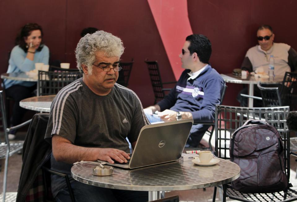 In this Friday, April 18, 2014 photo, Syrian novelist Khaled Khalifa writes a commentary for the pan-Arab daily newspaper Al-Hayat on the death of Colombian novelist Gabriel Garcia Marquez, at a cafe in Hamra Street, Beirut, Lebanon. Khalifa’s thoughts keep wandering back to his home and favorite place in the world, the northern city of Aleppo, Syria. For nearly two years now, Aleppo has been ravaged by brutal urban warfare between rebels and government forces, each holding roughly half the city. (AP Photo/Bilal Hussein)