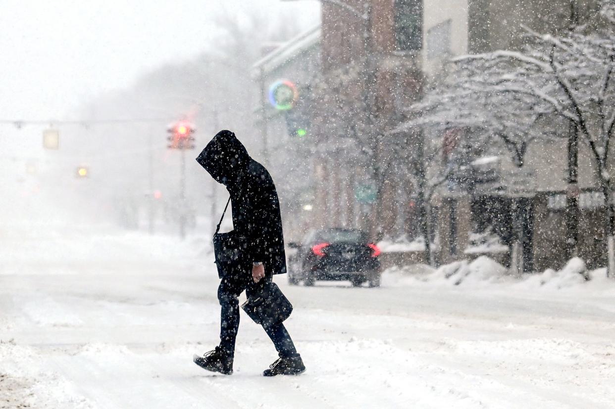 A pedestrian crosses Capitol Avenue at Allegan Street during a winter storm on the morning of Wednesday, Feb. 2, 2022, in Lansing.