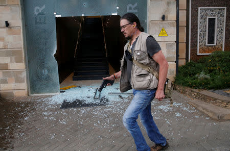 Serge Medic, the Swiss owner of a security company carries his pistol as he walks at the scene where explosions and gunshots were heard at the Dusit hotel complex in Nairobi, Kenya January 15, 2019. Picture taken January 15, 2019. REUTERS/Thomas Mukoya