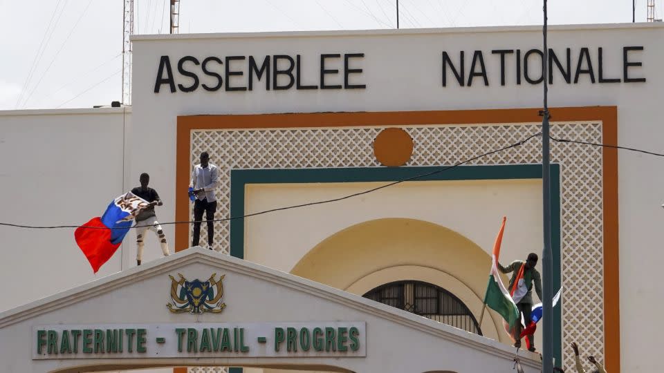 People with Niger and Russia flags climb the gate to the National Assembly building during a protest in Niamey.  - Issifou Djibo/EPA-EFE/Shutterstock