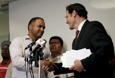 Attorney Steven Arenson (R) delivers a check to immigrant car wash worker Michel Rodriguez at a news conference, where 18 immigrant car wash workers received the final part of a $1.6 million federal court settlement for unpaid wages after a five-year case against four car washes in New York City and New Jersey, in Manhattan, New York City, U.S., June 21, 2016. REUTERS/Mike Segar