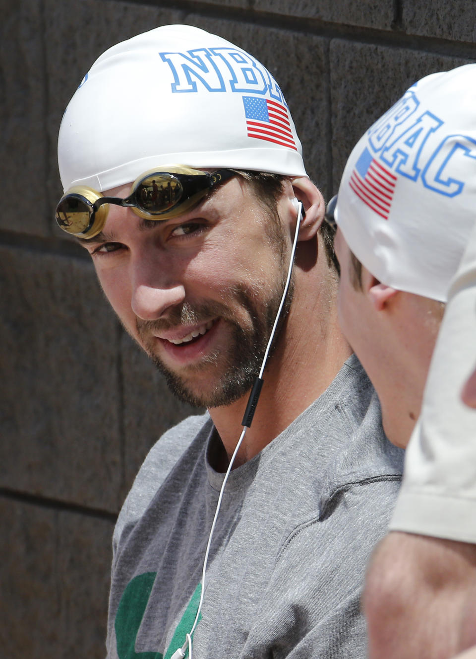 Michael Phelps listens to music prior to competing in the 100-meter butterfly during the Arena Grand Prix swim meet, Thursday, April 24, 2014, in Mesa, Ariz. It is Phelps' first competitive event after a nearly two-year retirement. (AP Photo/Matt York)