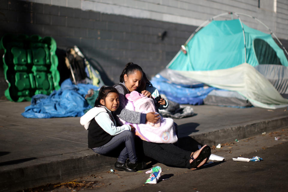 Samantha Cadena sits with her daughters as they wait in line with other needy families to receive free back-to-school supplies from the Fred Jordan Mission in Los Angeles. (Photo: Lucy Nicholson / Reuters)