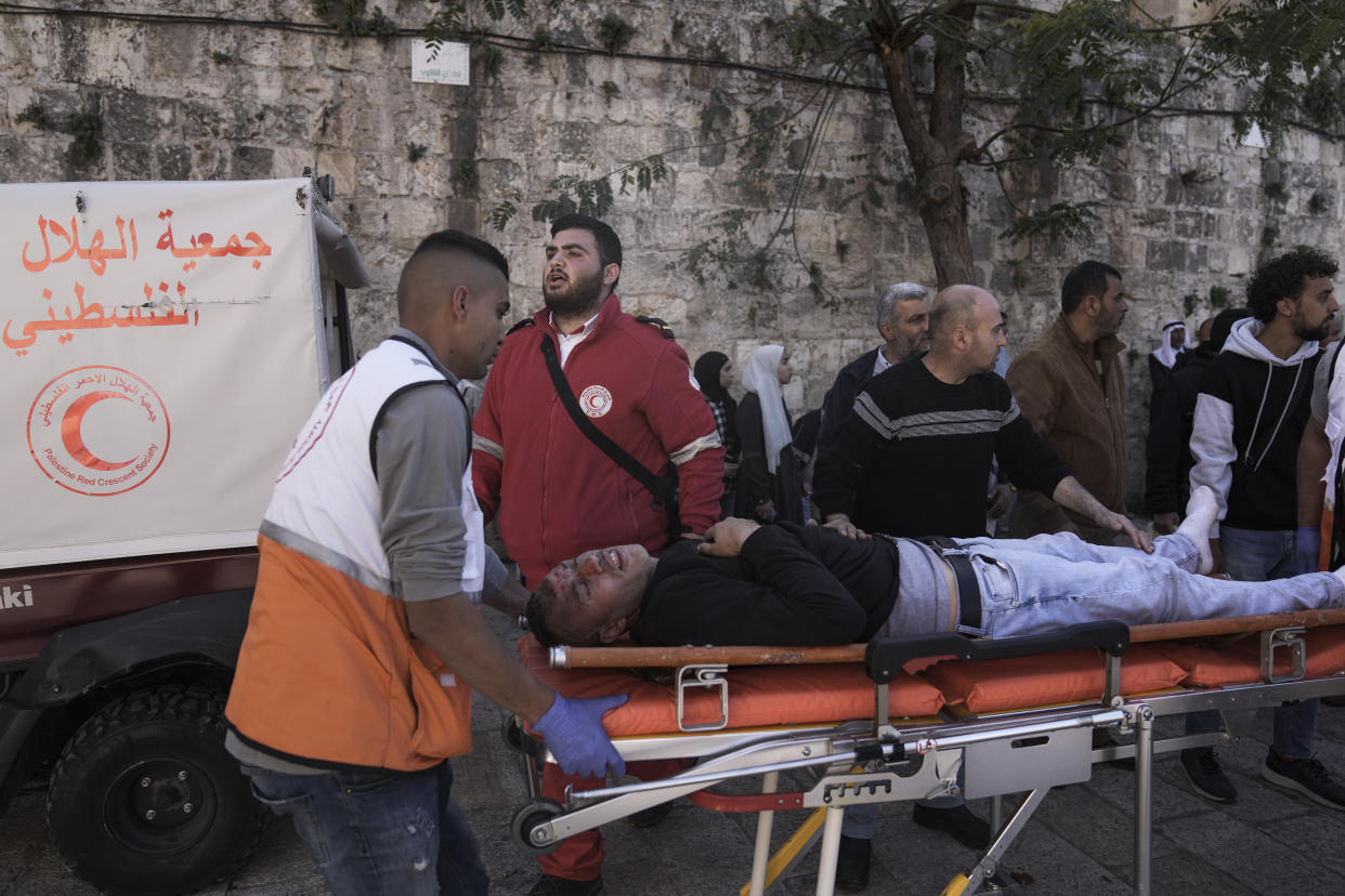 Medics evacuate an injured Palestinian man during clashes between Palestinian demonstrators and Israeli security forces, outside Al Aqsa Mosque compound in Jerusalem's Old City, Friday, April 15, 2022. (AP Photo/Ariel Schalit)