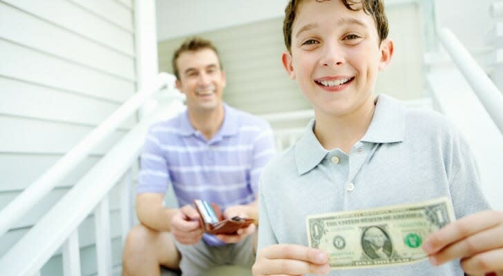 Boy, holding a dollar bill, with father