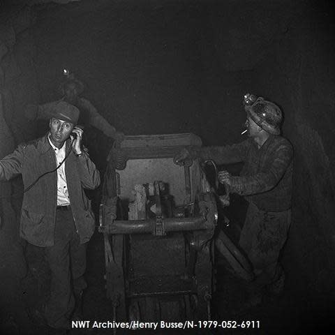 A black and white photo shows three men standing inside an underground stope at what was then called the Ridley Mines Holding Company uranium mine at Stark Lake.