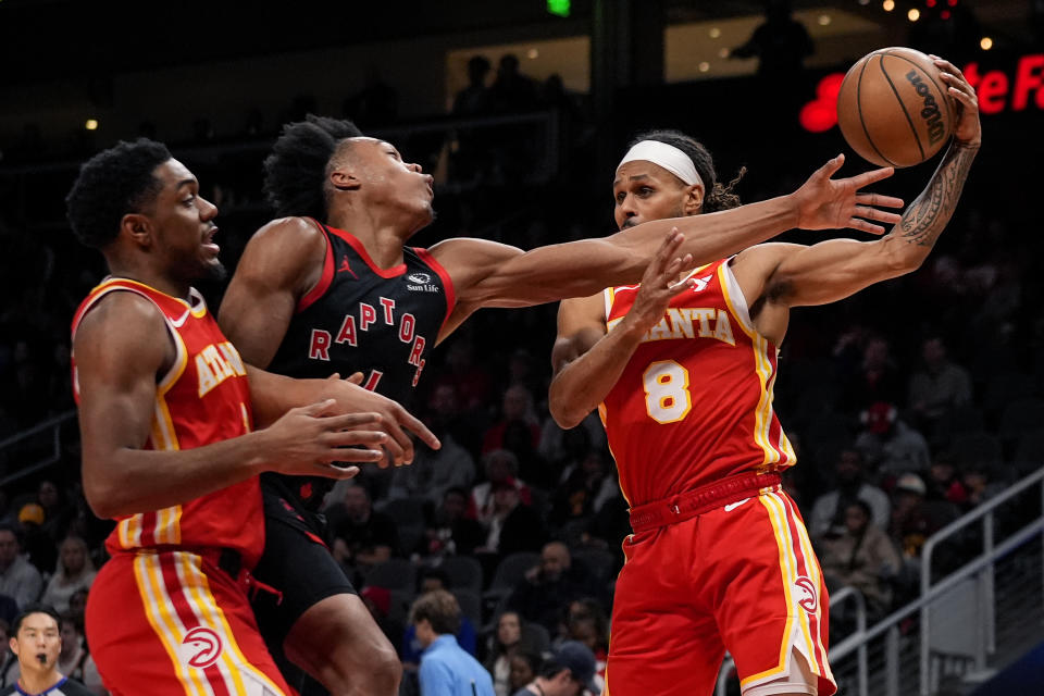 Atlanta Hawks guard Patty Mills (8) grabs a rebounds against Toronto Raptors forward Scottie Barnes (4) in the first half of an NBA basketball game Sunday, Jan. 28, 2024, in Atlanta. (AP Photo/John Bazemore)