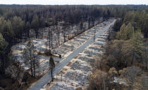 FILE - In this Dec. 3, 2018, file photo, homes leveled by the Camp Fire line the Ridgewood Mobile Home Park retirement community in Paradise, Calif. Pacific Gas and Electric says it has reached a $13.5 billion settlement that will resolve all major claims related to devastating wildfires blamed on its outdated equipment and negligence. The settlement, which the utility says was reached Friday, Dec. 6, 2019, still requires court approval. (AP Photo/Noah Berger, File)
