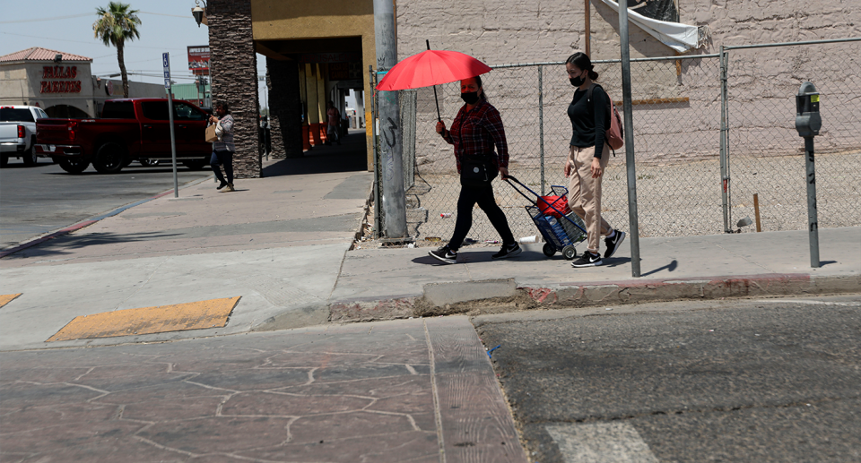 People shelter under umbrellas on a California street.