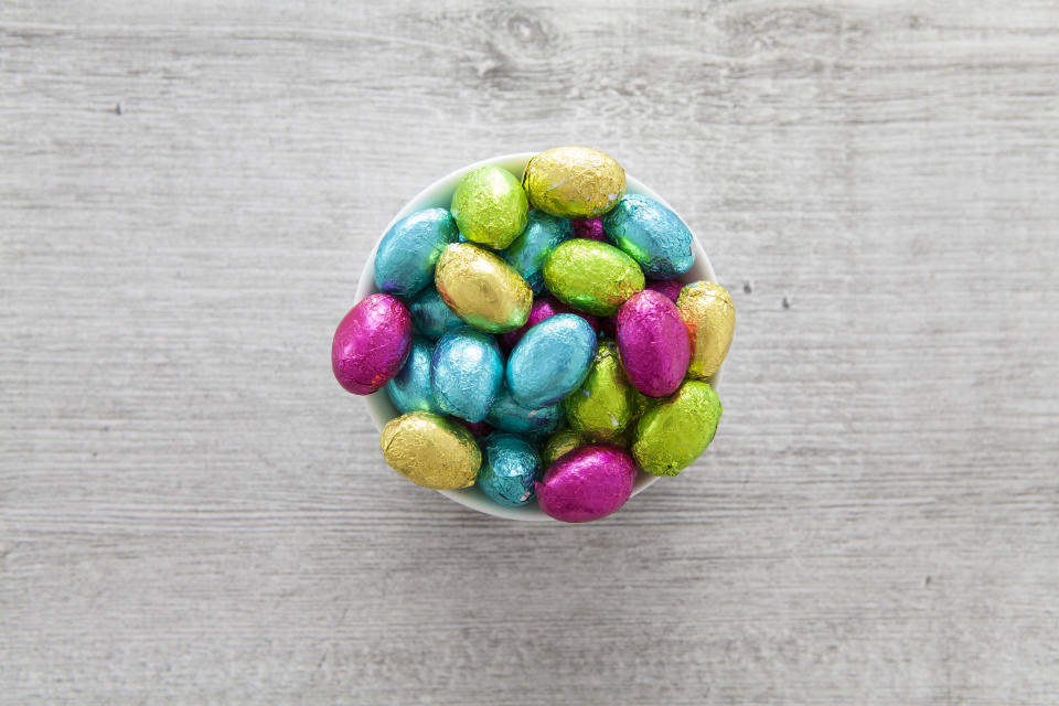 Brightly colored foil wrapped mini Easter eggs in a ramekin dish photographed from overhead