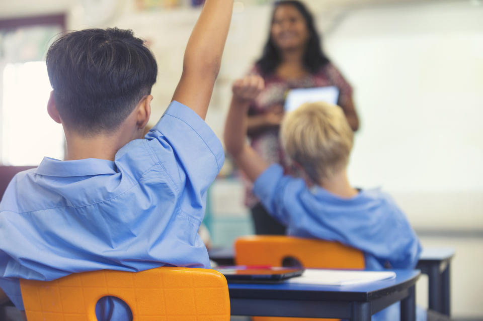 A child raises his hand in a classroom.