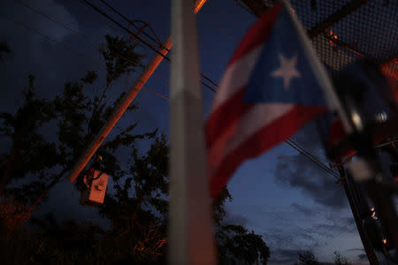 Puerto Rico's flag is seen as a worker of Puerto Rico's Electric Power Authority (PREPA) repairs part of the power grid after Hurricane Maria hit the area in September, in Manati, Puerto Rico October 30, 2017. REUTERS/Alvin Baez