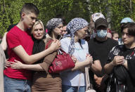 People react next to the grave of Elvira Ignatieva, an English language teacher who was killed at a school shooting on Tuesday in Kazan, Russia, Wednesday, May 12, 2021. Russian officials say a gunman attacked a school in the city of Kazan and Russian officials say several people have been killed. Officials said the dead in Tuesday's shooting include students, a teacher and a school worker. Authorities also say over 20 others have been hospitalised with wounds. (AP Photo/Dmitri Lovetsky)