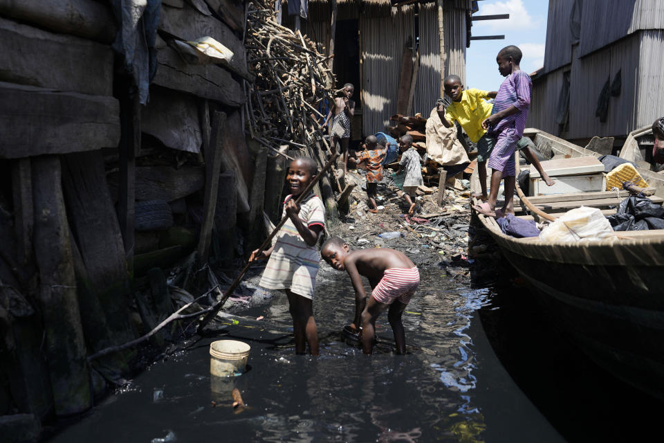 FILE - Children play in filthy water surrounded by garbage in Nigeria's economic capital Lagos' floating slum of Makoko, Monday, March. 20, 2023. Nigeria's President Bola Tinubu said Tuesday that his government will embark on “massive education” of youth as one way to tackle the increasing kidnappings for ransom now threatening the capital city along with the rest of the country's conflict-hit north. (AP Photo/Sunday Alamba, File)