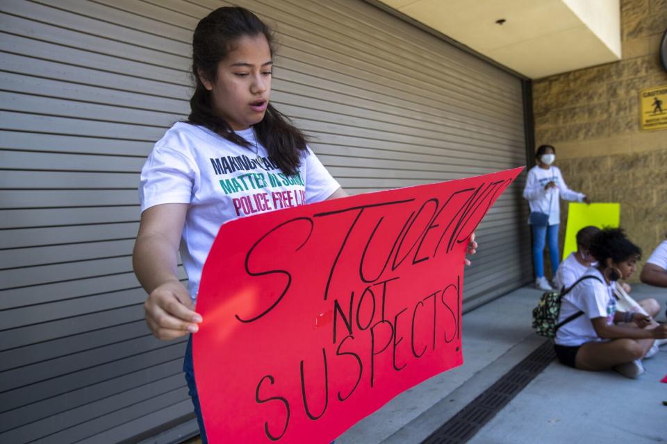 A female student holds a sign reading "students not suspects."