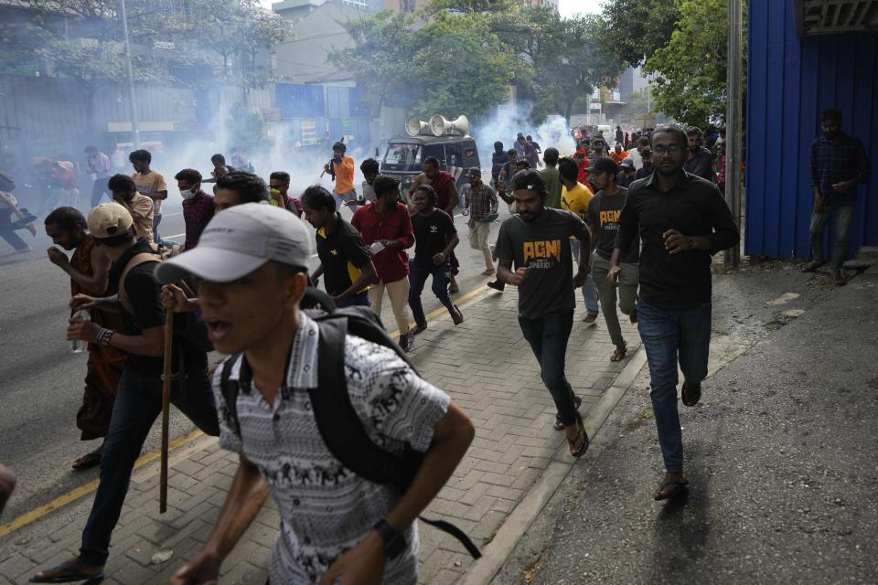 Anti-government protesters run as police fire tear gas and chase them during a protest march in Colombo, Sri Lanka, Thursday, Aug. 18, 2022. (AP Photo/Eranga Jayawardena)
