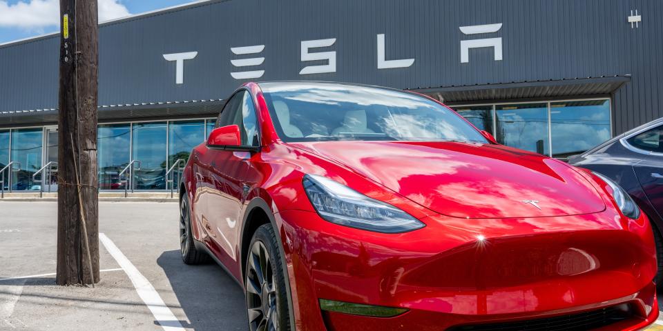 A red Tesla Model Y seen outside a Tesla showroom