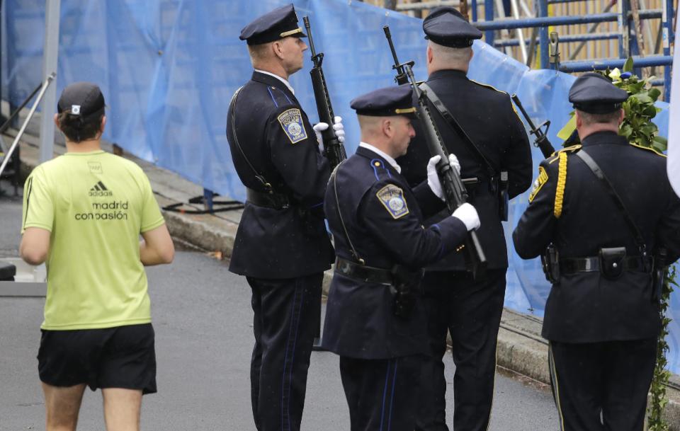 A runner passes as Boston Police honors change their post outside the Marathon Sports store, the site of the first of two bombs that exploded near the finish line of the 2013 Boston Marathon, Tuesday, April 15, 2014 in Boston. Three were killed and more than 260 injured in last year's explosions near the finish line of the race. (AP Photo/Charles Krupa)