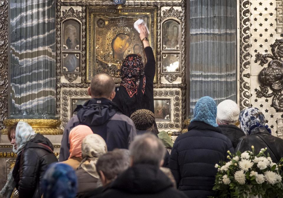 A church worker cleans an icon of the Kazan Mother of God as Orthodox believers gather for Sunday prayers, in the Kazansky Cathedral in St.Petersburg, Russia, Sunday, March 29, 2020. The leader of the Russian Orthodox Church is calling on believers to stay away from churches during the coronavirus pandemic and to pray at home instead. The new coronavirus causes mild or moderate symptoms for most people, but for some, especially older adults and people with existing health problems, it can cause more severe illness or death. (AP Photo/Dmitri Lovetsky)