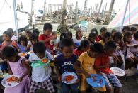 Children eat their free meals during Christmas celebrations at the town of Bislig, Tanauan in Leyte province, central Philippines December 24, 2013, a month after Typhoon Haiyan battered central Philippines. Super typhoon Haiyan reduced almost everything in its path to rubble when it swept ashore in the central Philippines on November 8, killing at least 6,069 people, leaving 1,779 missing and 4 million either homeless or with damaged homes. REUTERS/Romeo Ranoco (PHILIPPINES - Tags: DISASTER SOCIETY FOOD)