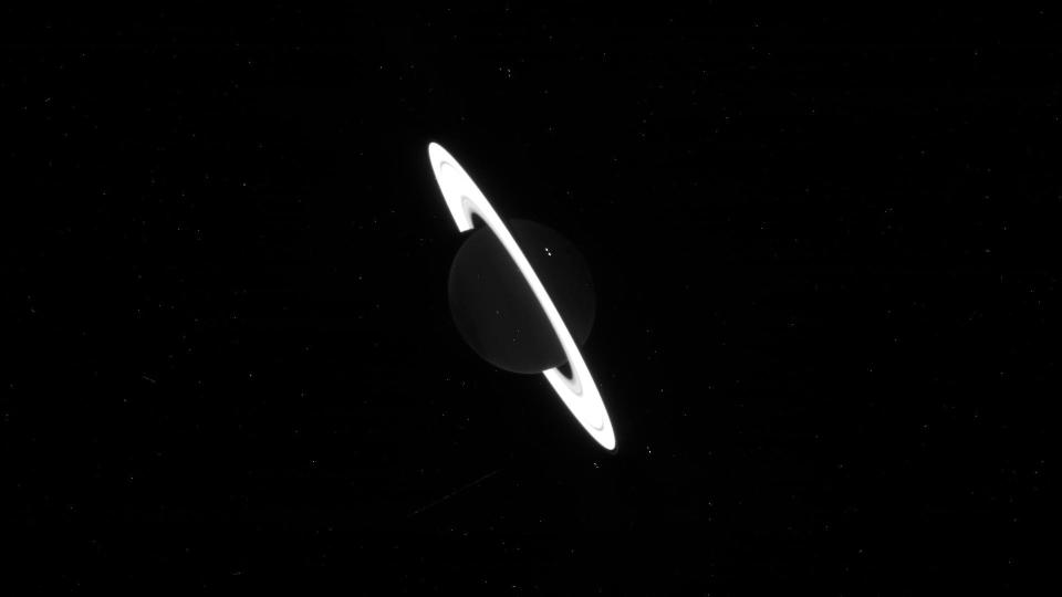 a black and white picture of saturn with the rings glowing bright white.