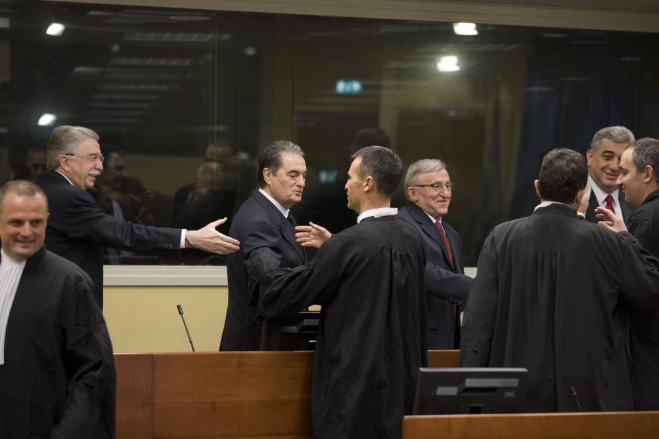 Nikola Sainovic, Nebojsa Pavkovic, Vladimir Lazarevic, and Sreten Lukic, rear row from left to right, greet members of their defense team in the court room of the Yugoslav war crimes tribunal in The Hague Thursday Jan. 23, 2014. Four former high-ranking Yugoslav and Serbian political, military and police officials who were convicted in 2009 for crimes committed against Kosovo Albanians in 1999 during Serbia’s deadly crackdown on ethnic Albanians appeared in court at the Yugoslav war crimes tribunal ahead of a decision in their appeal. (AP Photo/Peter Dejong, Pool)