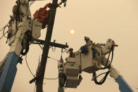 FILE - In this Nov. 9, 2018 file photo, Pacific Gas & Electric crews work to restore power lines in Paradise, Calif. Pacific Gas and Electric says it has reached a $13.5 billion settlement that will resolve all major claims related to devastating wildfires blamed on its outdated equipment and negligence. The settlement, which the utility says was reached Friday, Dec. 6, 2019, still requires court approval. (AP Photo/Rich Pedroncelli, File)
