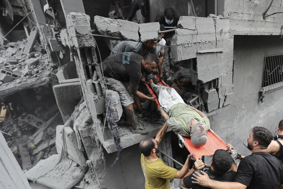 Palestinians carry an injured man out of the destruction following Israeli airstrikes on Gaza City, Friday, Oct. 27, 2023. (AP Photo/Abed Khaled)