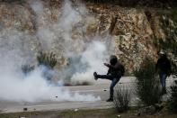 A demonstrator, who opposes the building of a new closed migrant detention centre, kicks back a tear gas canister at riot police during clashes, in the area of Diavolorema on the island of Lesbos