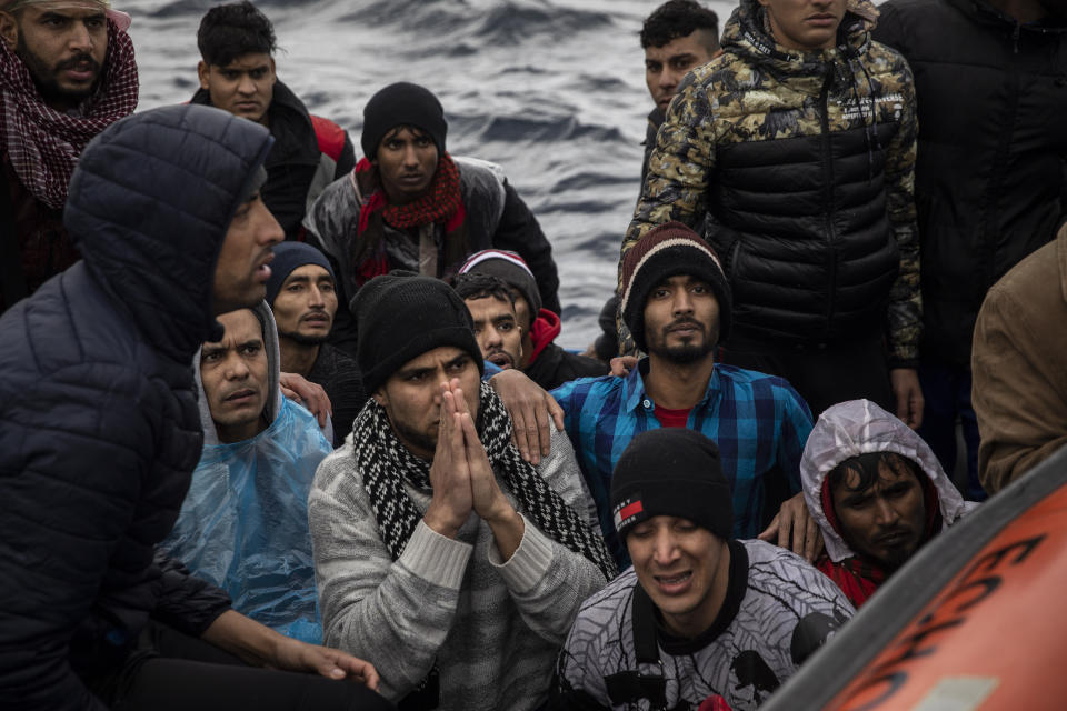 Men from Morocco and Bangladesh are assisted by members of Spanish NGO Open Arms on an overcrowded wooden boat in the Mediterranean Sea, international waters, off the Libyan coast, Friday, Jan. 10, 2020. (AP Photo/Santi Palacios)