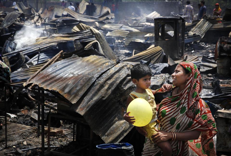 An Indian woman carries her child as she watches her burnt house after a fire at a slum in New Delhi, India, Friday, April 25, 2014. A massive fire ripped through a New Delhi slum Friday, destroying nearly 500 thatched huts and leaving already impoverished families homeless, said a fire department official. Seven people were hospitalized with minor burn wounds. (AP Photo/Manish Swarup)