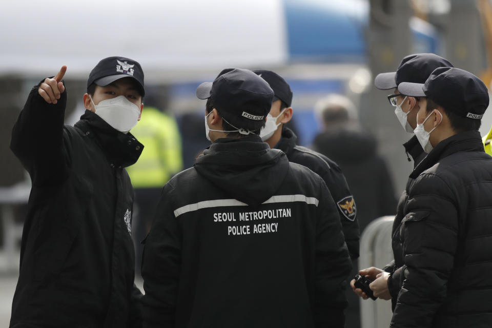 Police officers wearing face masks talk ahead of a rally in downtown Seoul, South Korea, Saturday, Feb. 22, 2020. South Korea on Saturday reported a six-fold jump in viral infections in four days to 346, most of them linked to a church and a hospital in and around the fourth-largest city where schools were closed and worshipers and others told to avoid mass gatherings. (AP Photo/Lee Jin-man)
