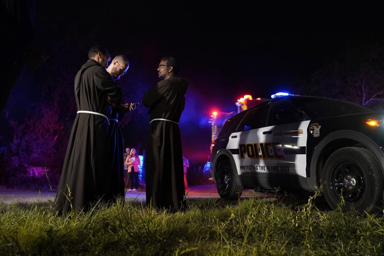 Priests gather near the scene where officials say dozens of people have been found dead and multiple others were taken to hospitals with heat-related illnesses after a semitrailer containing suspected migrants was found on Monday, June 27, 2022, in San Antonio.