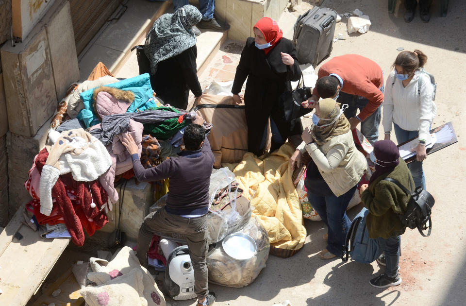 Neighbors guard belongings of victims at the site of the collapsed apartment building in the el-Salam neighborhood, in Cairo, Egypt, Saturday, March 27, 2021. A nine-story apartment building collapsed in the Egyptian capital early Saturday, killing at several and injuring about two dozen others, an official said. (AP Photo/Tarek wajeh)