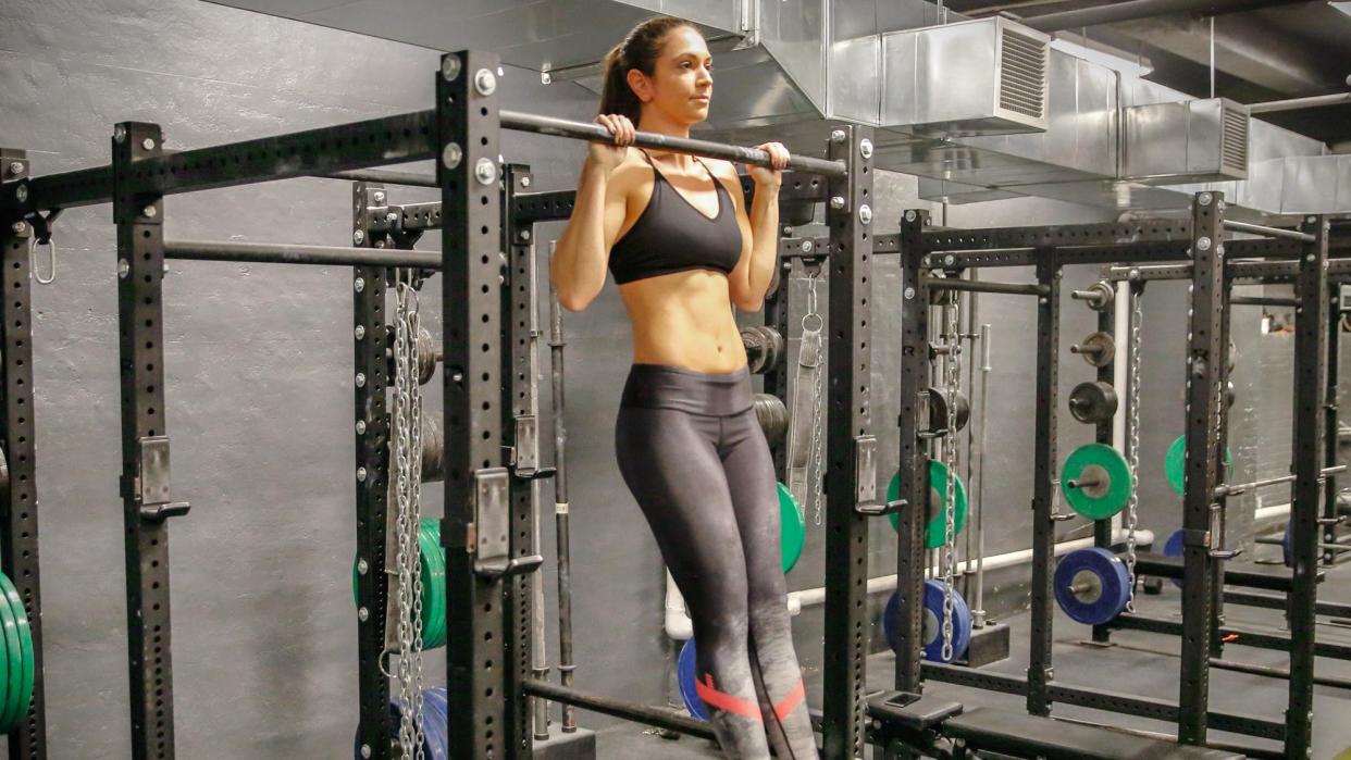  Woman performing a pull-up at a gym. 
