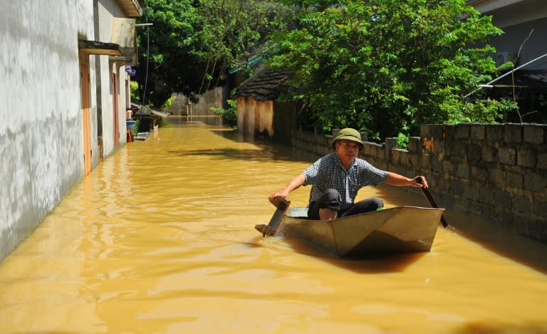 A Vietnamese villager crosses a flooded alley using a boat in the northern province of Ninh Binh, on October 12, 2017