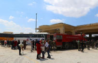 People, who were evacuated from the two rebel-besieged Shi'ite villages of al-Foua and Kefraya, stand near buses at insurgent-held al-Rashideen, Aleppo province, Syria April 19, 2017. REUTERS/Ammar Abdullah