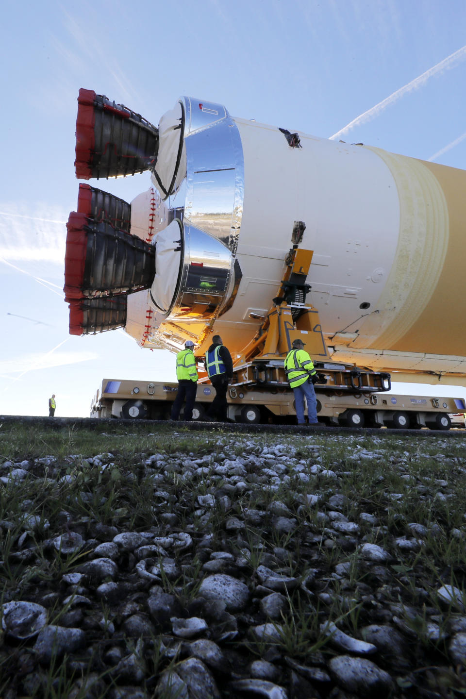 Security and safety personnel walk with the core stage of NASA's Space Launch System rocket, that will be used for the Artemis 1 Mission, as it is moved to the Pegasus barge, at the NASA Michoud Assembly Facility where it was built, in New Orleans, Wednesday, Jan. 8, 2020. It will be transported to NASA's Stennis Space Center in Mississippi for its green run test. (AP Photo/Gerald Herbert)