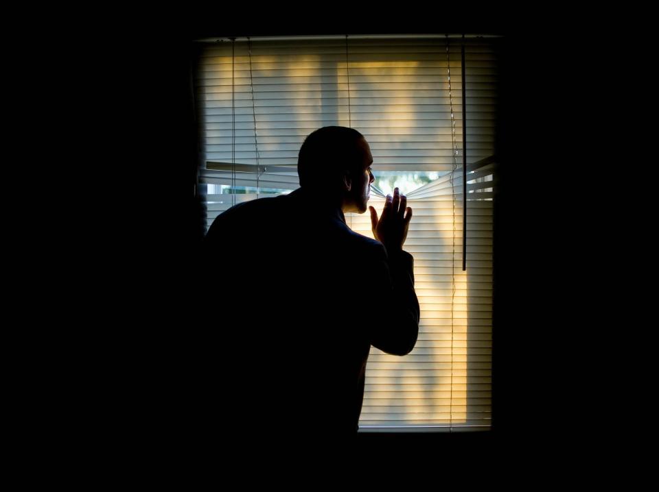 scared man looking through blinds
