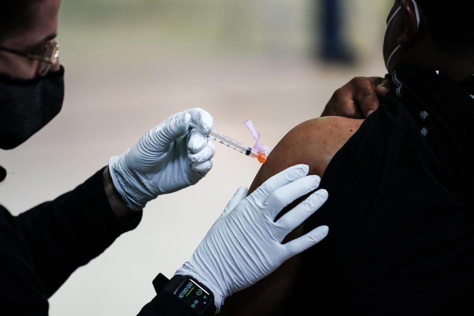 FILE - In this March 26, 2021, file photo, a member of the Philadelphia Fire Department administers the Johnson & Johnson COVID-19 vaccine to a person at a vaccination site setup at a Salvation Army location in Philadelphia. A new poll from The Associated Press-NORC Center for Public Affairs Research shows that the percentage of Americans resisting getting inoculated has shrunk in the past few months. But it’s still not enough to pull America out of the pandemic, and reach herd immunity. (AP Photo/Matt Rourke, File)